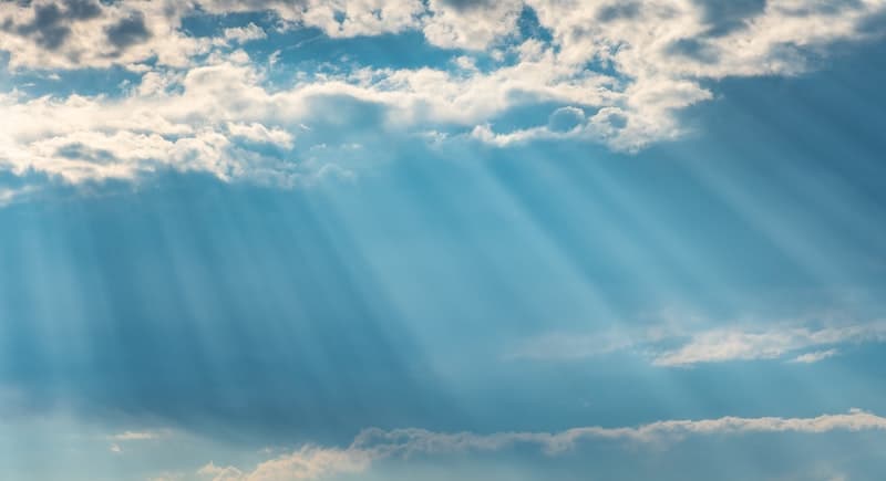 The sun shining in a partly cloudy sky